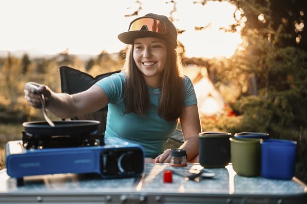 Camping enthusiast cooking outside on a stove