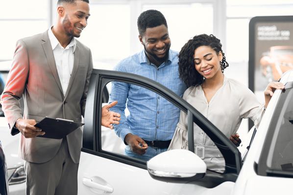 Couple looking at a new car with car sales person
