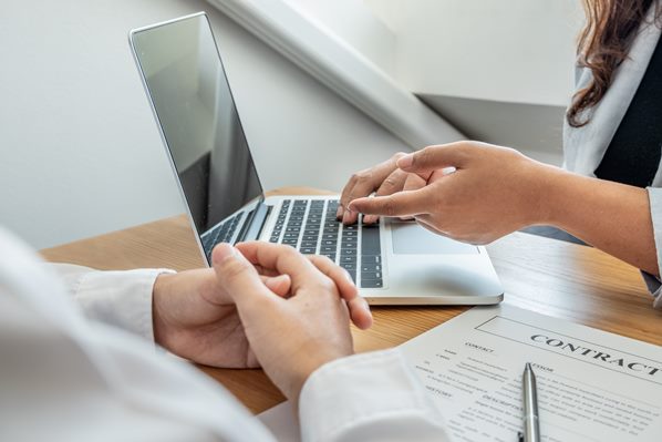 Manager writing a contract on his laptop